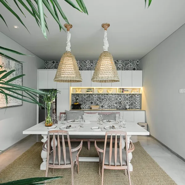 Dining table under rattan pendant lights with the open kitchen behind